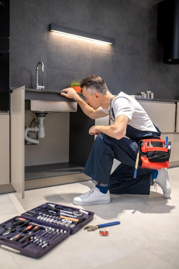 man-kneeling-down-touching-sink-inspecting-pipes_259150-58251