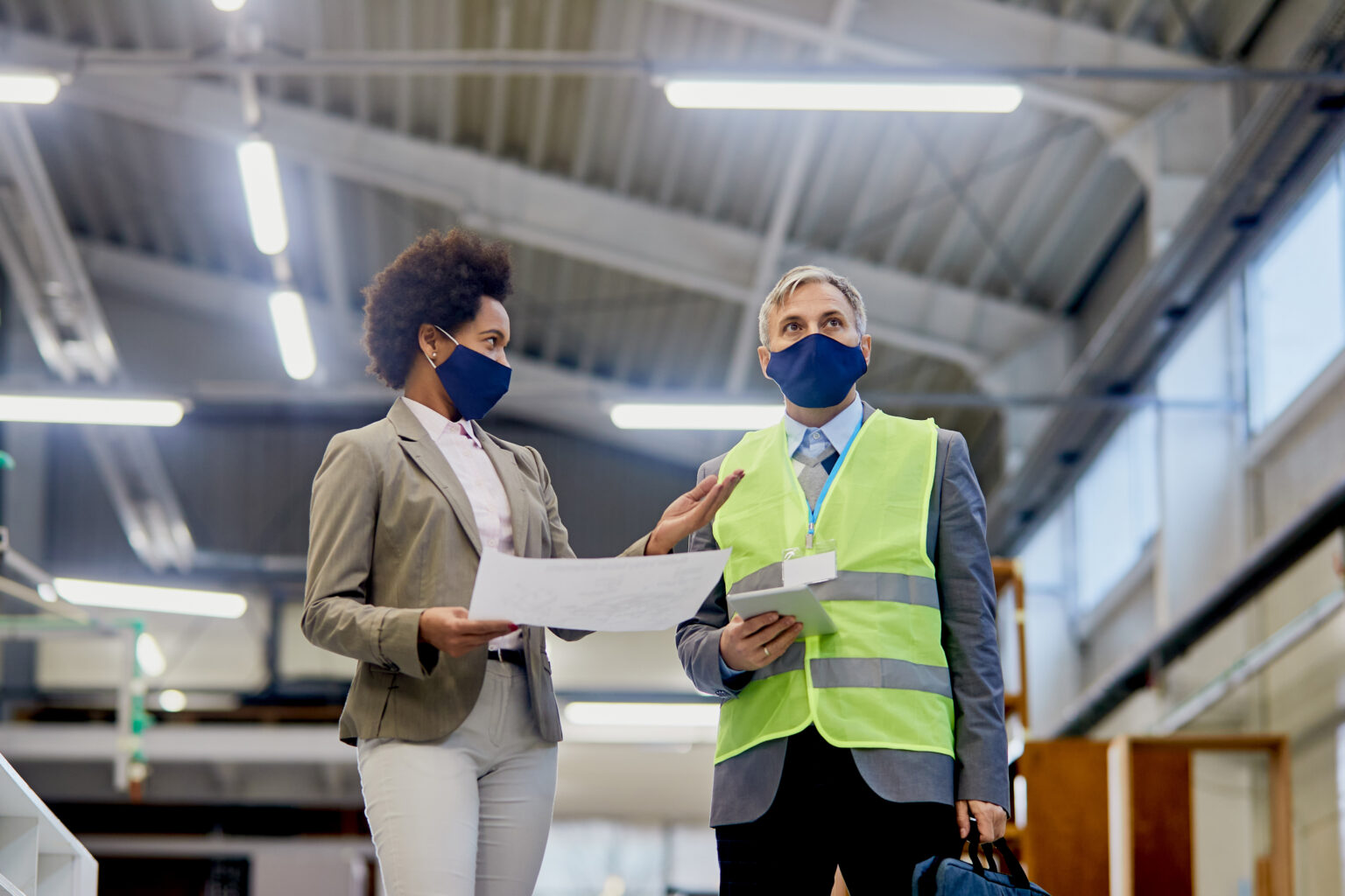 view-black-businesswoman-talking-quality-control-inspector-who-is-visiting-factory-during-coronavirus-pandemic-1536x1024 (1)