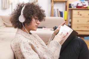 side-view-teenager-reading-book-listening-music (1)